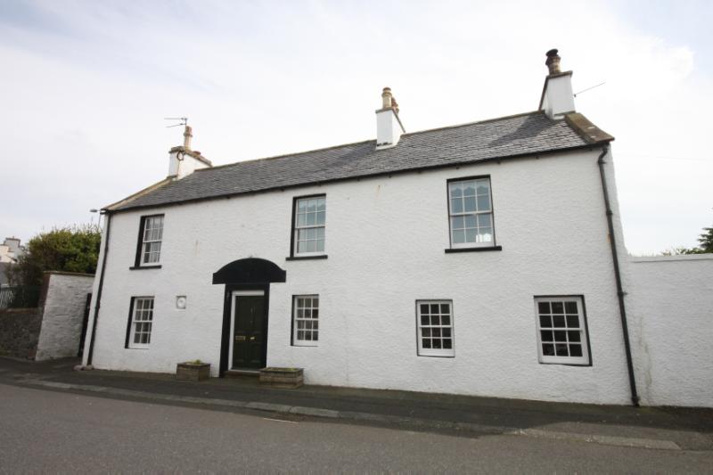 2 Commercial Street, Port William, north elevation facing street, looking south, on a sunny day, with black painted doorway surround and widely spaced windows