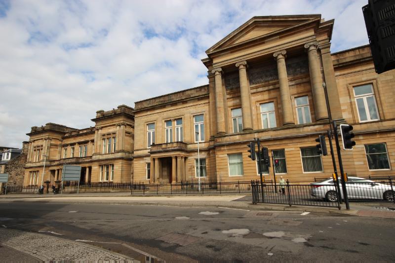 Paisley Sheriff Court and Justice of the Peace Court, principal elevation, looking north, during daytime on cloudy day, with traffic lights and road signs in front of the building. 