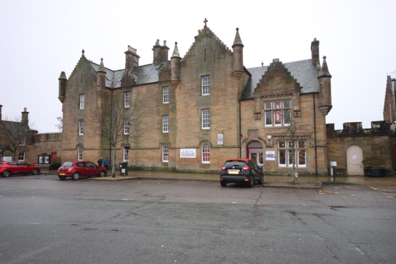 Old Jail and Former Drill Hall principal elevation, looking south, during daytime, on an overcast day and with red and black cars in front of building.