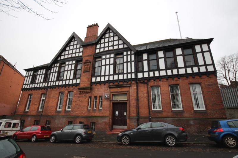 Jardine Street, principal elevation, looking west, with parked cars infront of the building during daytime with grey skies