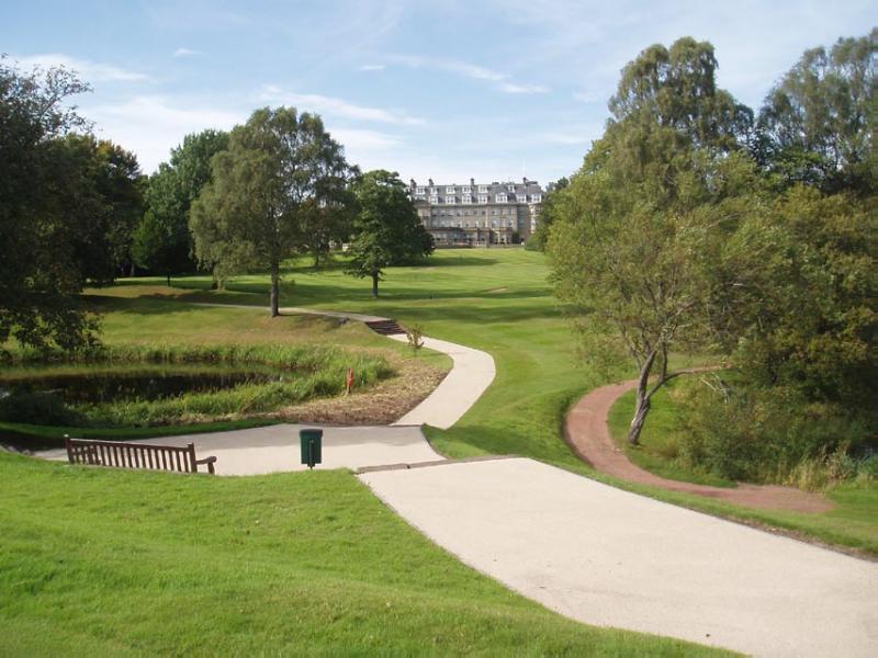 General view of Gleneagles Hotel and gardens, looking north in daytime with grass and path