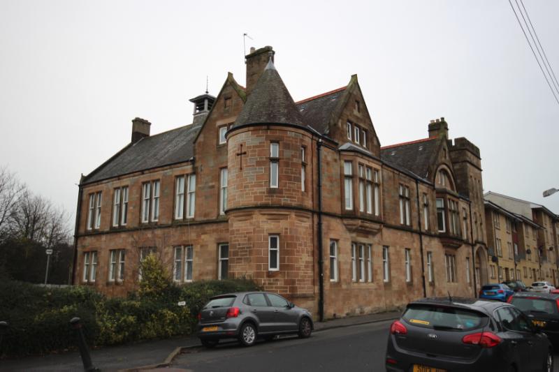31 and 33 Coplaw Street principal elevation, looking east towards the southwest corner of the building, with cars in the foreground,during daytime on a dull day