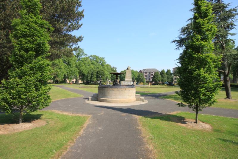 Drinking Fountain, Zetland Park, looking north, during daytime, on clear day with blue sky, green grass and trees. 