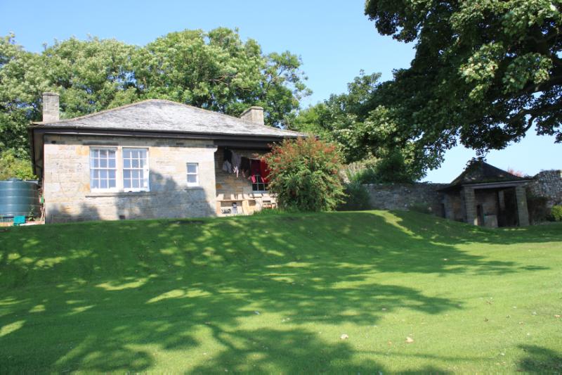 Custodian’s House, front (southeast facing) elevation, grass lawn to front, on clear day with blue sky. 