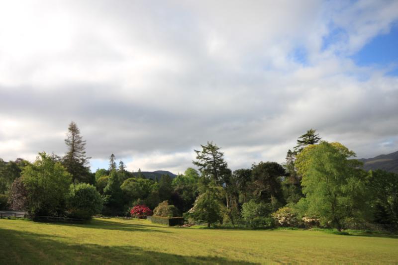 Leckmelm Gardens, looking south from walled garden area on partly cloudy day with blue sky.