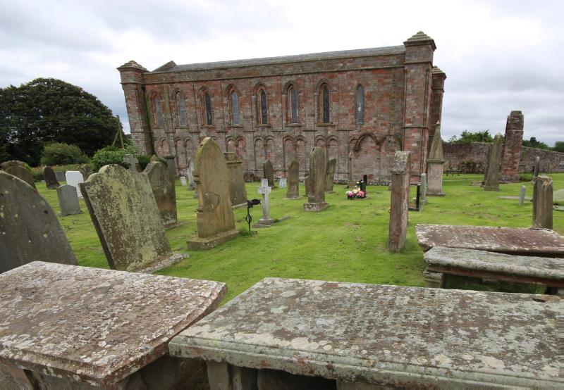 Coldingham Priory Church and graveyard looking south during daytime on a cloudy day.