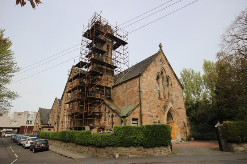 Former Maryhill High Church and Halls with green hedge in foreground and cars to left on grey overcast day.
