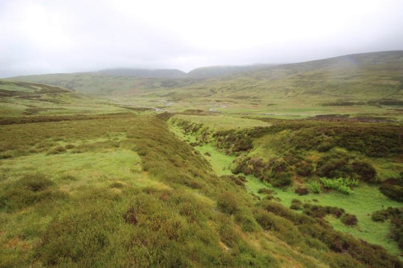 Gold scours, north of the Shortcleuch Water, Leadhills looking south down a hushing during daytime, on an overcast day with rain.