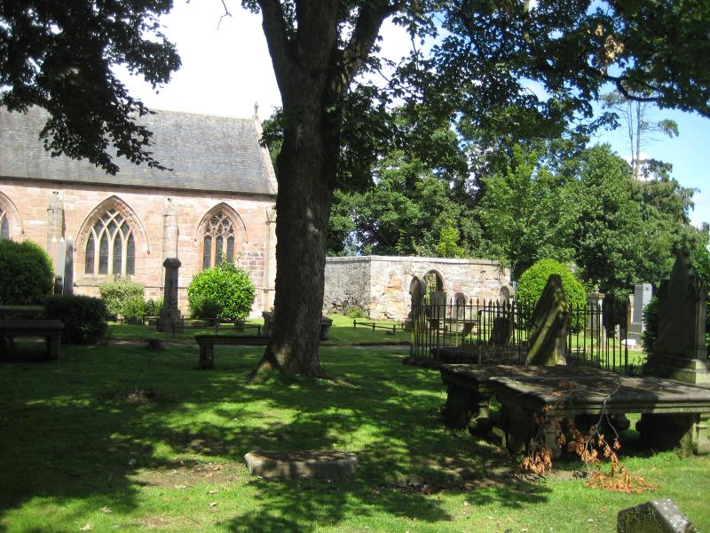 Tain, remains of old parish church and burial ground with roofed collegiate church in background, in day time with a blue sky.