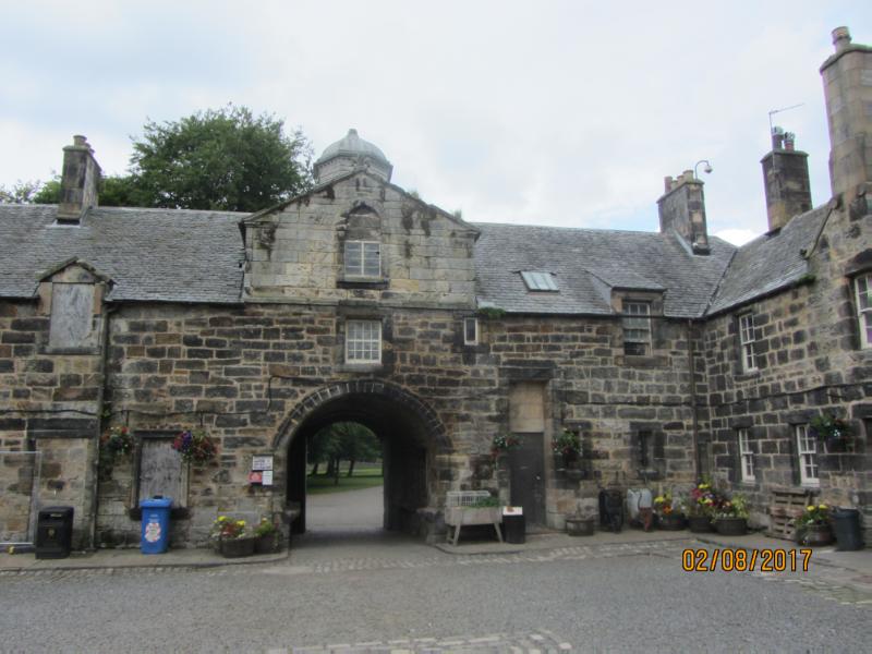Interior of Pollok stable complex, looking northwest through entrance archway, in daylight, cloudy sky