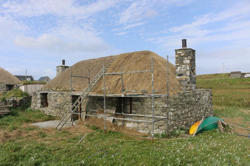 7a Ruisgarry, southwest elevation, looking northeast, during daytime, on clear day with blue sky and white clouds, with neighbouring cottage in view.