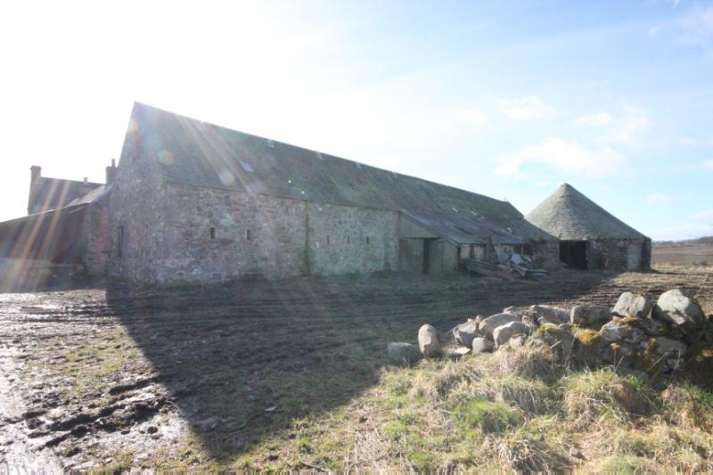 Former horsemill and attached rectangular-plan steading building at Kinvaid Farm, north elevation, looking southwest, during daytime on a sunny day with a farm track in front. 