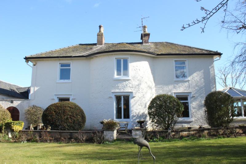 Craigview House, southwest elevation, looking northeast, with a metal sculpture on the lawn and shrubbery in front of the house, during daytime. 