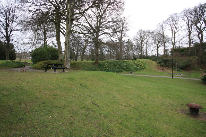 Castledykes Park, motte and bailey, medieval castle and associated earthworks, looking south-east towards Castle Hill, on an overcast day. 