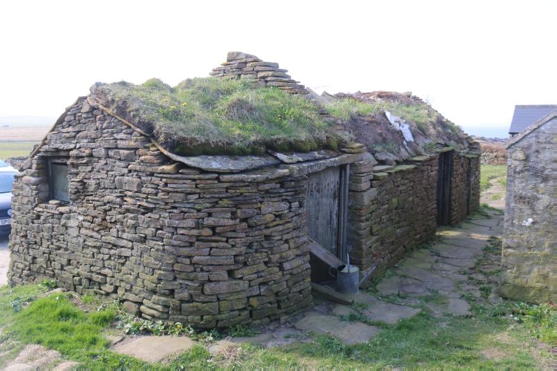 Detached byre to south of farmhouse, looking south, during daytime, on clear day with white sky.