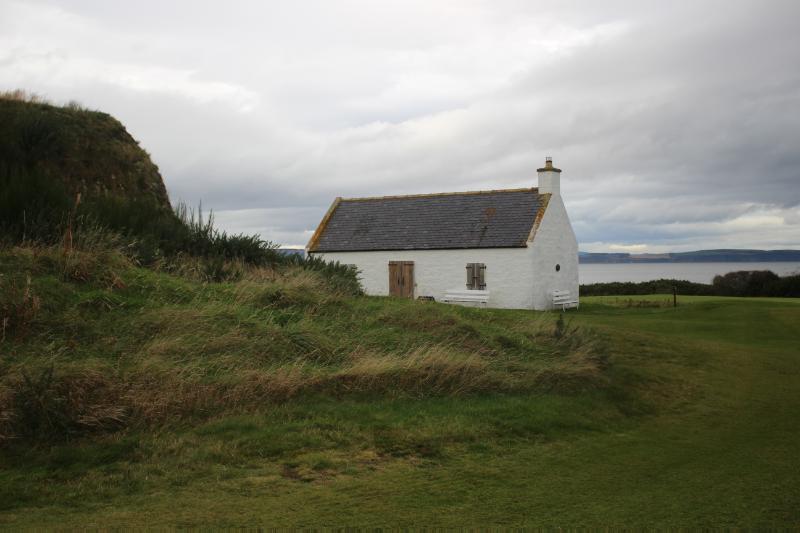 Front elevation of the bothy, looking northwest over the Moray Firth with the turfed ice house in the front left foreground and the Moray Firth in the background.
