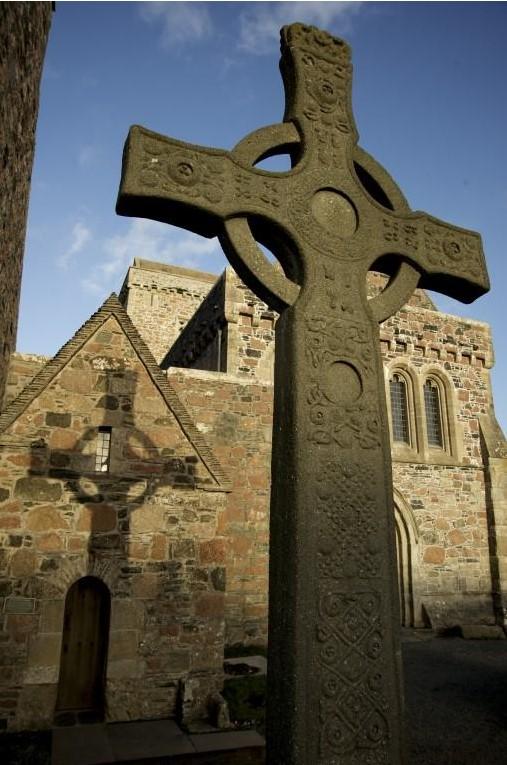 Replica of St John's Cross, casting a shadow on St Columba's shrine at Iona Abbey.
