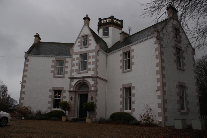 Battleblent House, principal (northwest) elevation, with hexagonal tower behind the entrance gable, looking southeast, during daytime, on overcast day. 