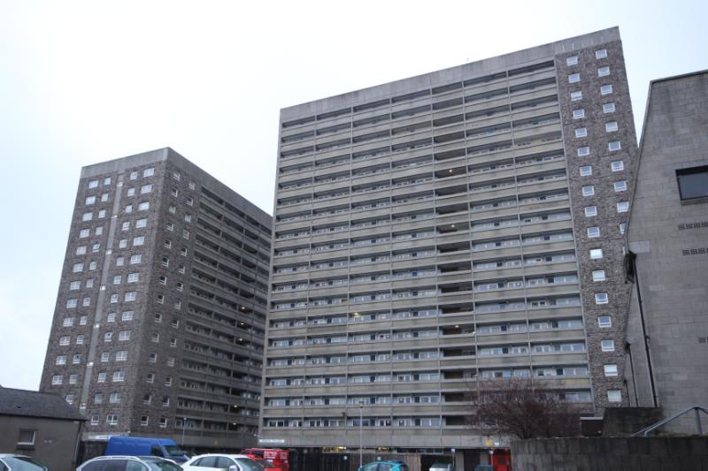 Hutcheon Court (left) and Greig Court (right) west elevations, looking east, during daytime, with cloudy sky, tree and parked cars to foreground