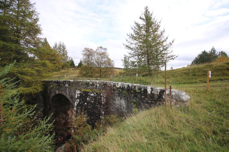 Bridge carrying former military road over Allt Anndeir in landscape looking east on an overcast day. 