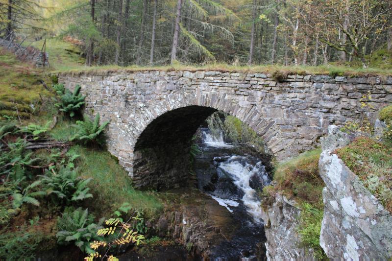 View of south elevation of Bridge in Clunes Wood carrying former military road over Allt a' Chrombaidh within woodland.