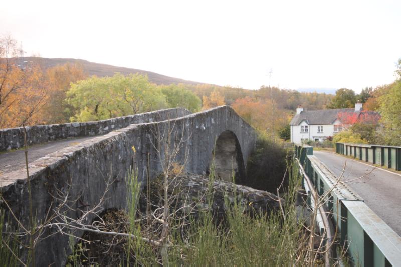 General view of Tummel military road bridge taken from the northeast with replacement road bridge to south and a with house in the background. 