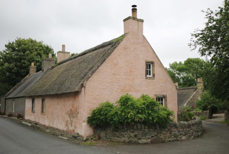 West End and West End Cottage, Collessie, looking east, during daytime with a bush and rubble wall infront of the gable of the cottage