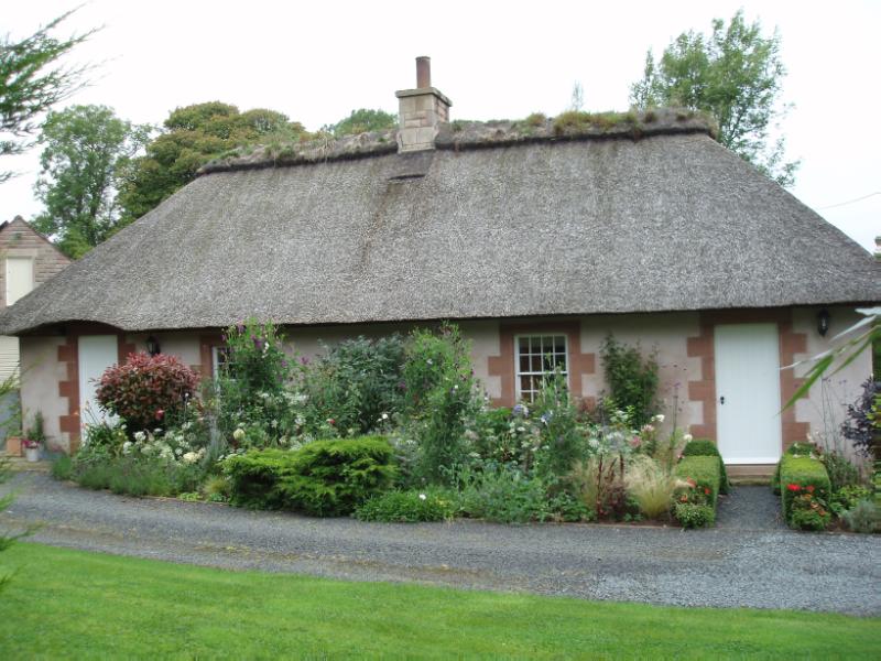 Thatched Cottage, principal elevation, looking northwest, during daytime, on clear day with blue sky. 