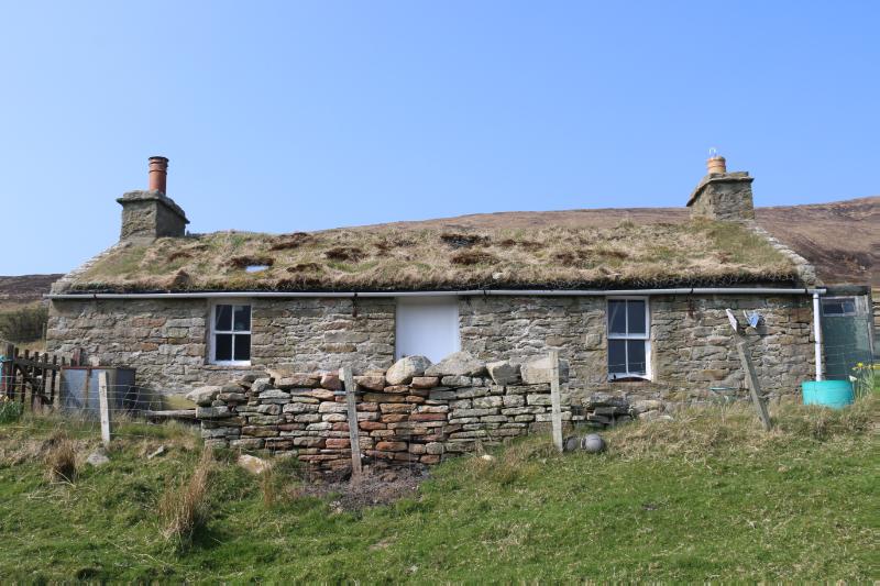 The Mount, principal elevation of cottage looking west, with Moor Fea hill rising to rear, on a dry day with blue sky