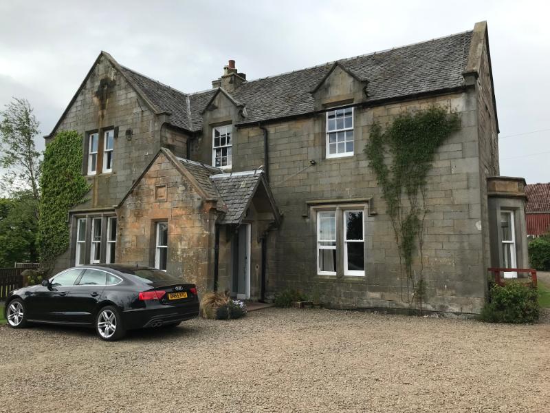 Haugh Farmhouse, entrance elevation, looking west, during daytime, on overcast day, with a car in the foreground.