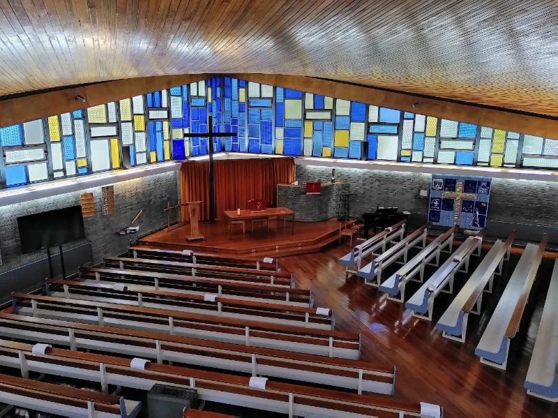 Interior of Boghall Parish Church, looking southwest towards the chancel from the gallery with angled pews and coloured glass of clerestory.