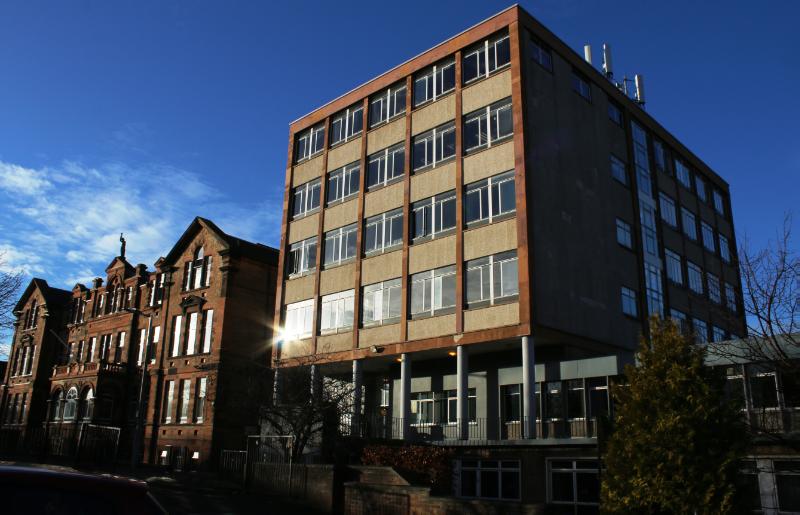 Trinity Academy, 6-storey classroom block and 2-storey podium block to right and 1891-3 building to left, looking northwest during daytime with blue sky. 