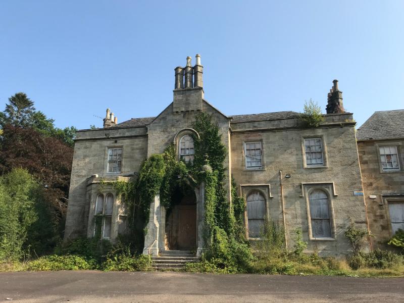 Braidwood House, principal elevation, looking northeast, with blue skies and driveway in the foreground.