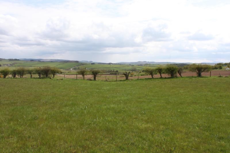 Two henges, 175m NE and 410m WSW of Lindston House looking southeast, during daytime. The ditch of the henge can be seen on either side of the image as a dip in the modern fence line. 