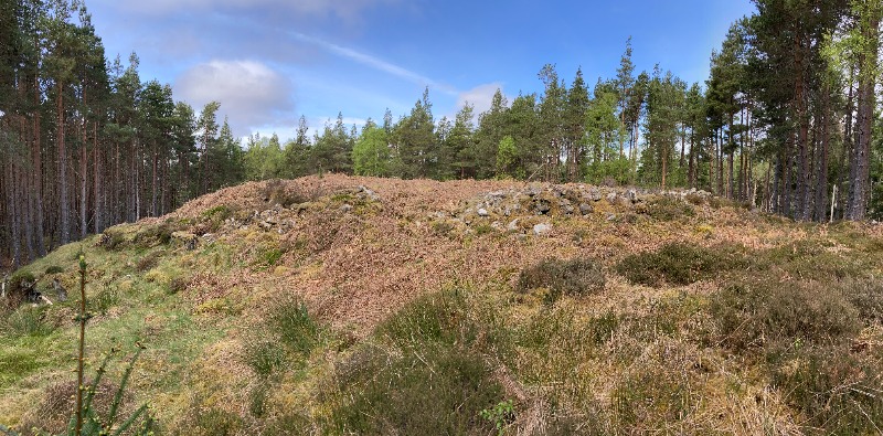 Carn Na Buaile fort, 780m NNW of Comrie looking north west, showing the position of an entrance, on a clear day with blue sky.  
