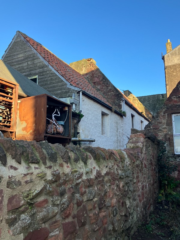 86 and 88 Hight Street, Dunbar, rear elevation, looking northeast, during daytime, on a clear day with blue sky and a rubble wall in the foreground. 