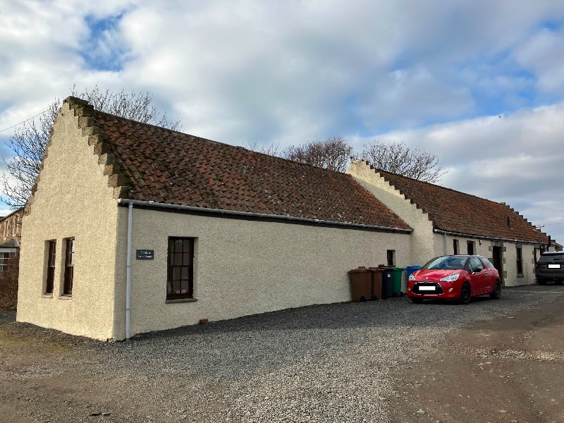 The Barn Easter Grange, principal elevation, looking northwest, during daytime, on a cloudy day with two cars parked in front. 